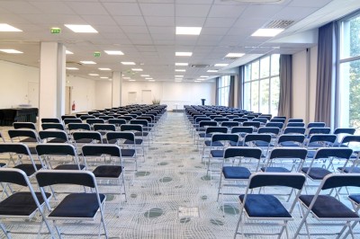 Plusieurs Citroën 2CV colorées alignées sur un parking ensoleillé.