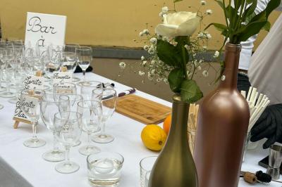 Table dressée avec des verres, bouteilles décoratives, une rose blanche et des citrons, devant un panneau ’Bar’.