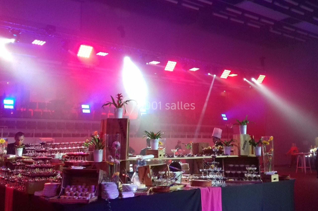 Buffet décoré avec des plats variés dans une salle éclairée par des lumières colorées, ambiance événementielle.