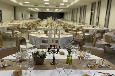 Salle de réception décorée avec des tables rondes, nappes blanches, chandeliers et compositions florales.