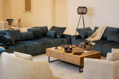 Salle à manger et salon avec table en bois, canapés clairs, lampes suspendues et lumière naturelle.