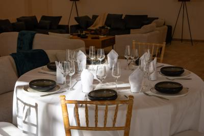 Salle à manger et salon avec table en bois, canapés clairs, lampes suspendues et lumière naturelle.