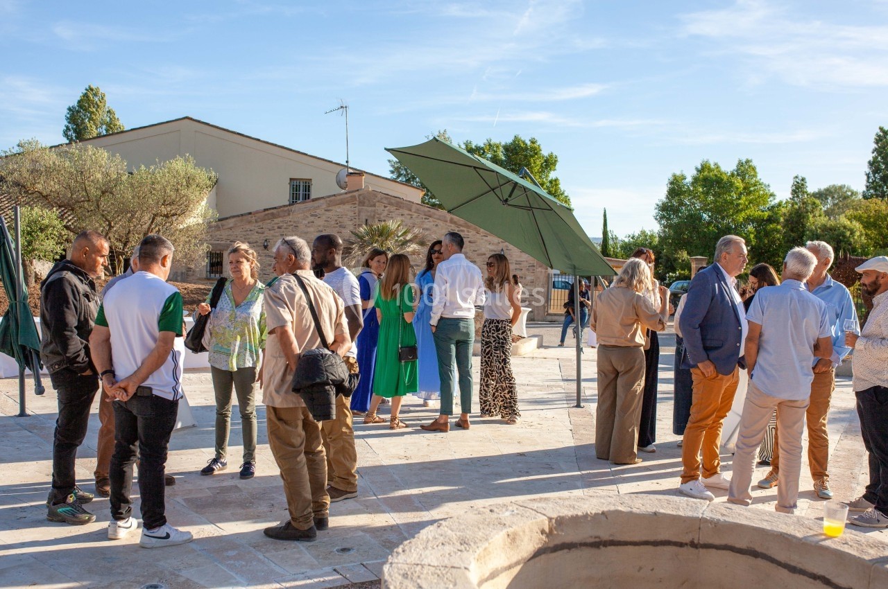 Groupe de personnes discutant en extérieur lors d'un événement, sous un ciel dégagé avec des arbres en arrière-plan.