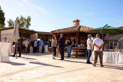 Salle à manger et salon avec table en bois, canapés clairs, lampes suspendues et lumière naturelle.