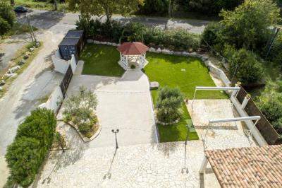 Allée pavée éclairée par des guirlandes lumineuses, menant à une pergola blanche dans un jardin nocturne.