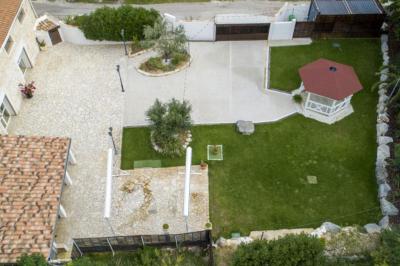 Allée pavée éclairée par des guirlandes lumineuses, menant à une pergola blanche dans un jardin nocturne.