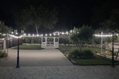 Allée pavée éclairée par des guirlandes lumineuses, menant à une pergola blanche dans un jardin nocturne.