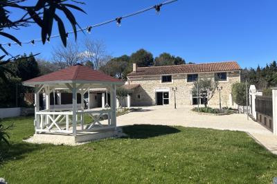 Allée pavée éclairée par des guirlandes lumineuses, menant à une pergola blanche dans un jardin nocturne.