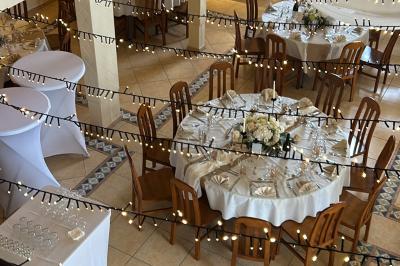 Allée pavée éclairée par des guirlandes lumineuses, menant à une pergola blanche dans un jardin nocturne.