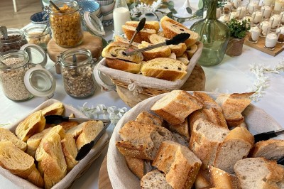 Plateau de mini-sandwiches variés, wraps et brochettes apéritives avec tomates cerises, présenté dans une boîte ouverte.