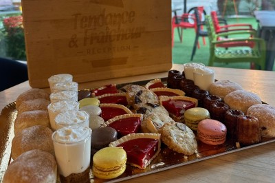 Plateau de mini-sandwiches variés, wraps et brochettes apéritives avec tomates cerises, présenté dans une boîte ouverte.