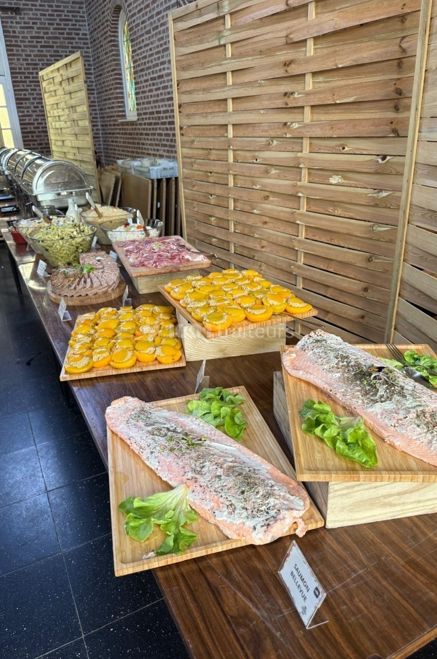 Buffet avec filets de saumon, tranches d'agrumes, salades et autres plats disposés sur une table en bois.