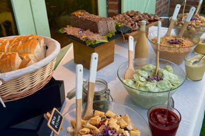 Buffet avec pain, pâté, salades variées, pâtes, sauces et condiments disposés sur une table blanche.