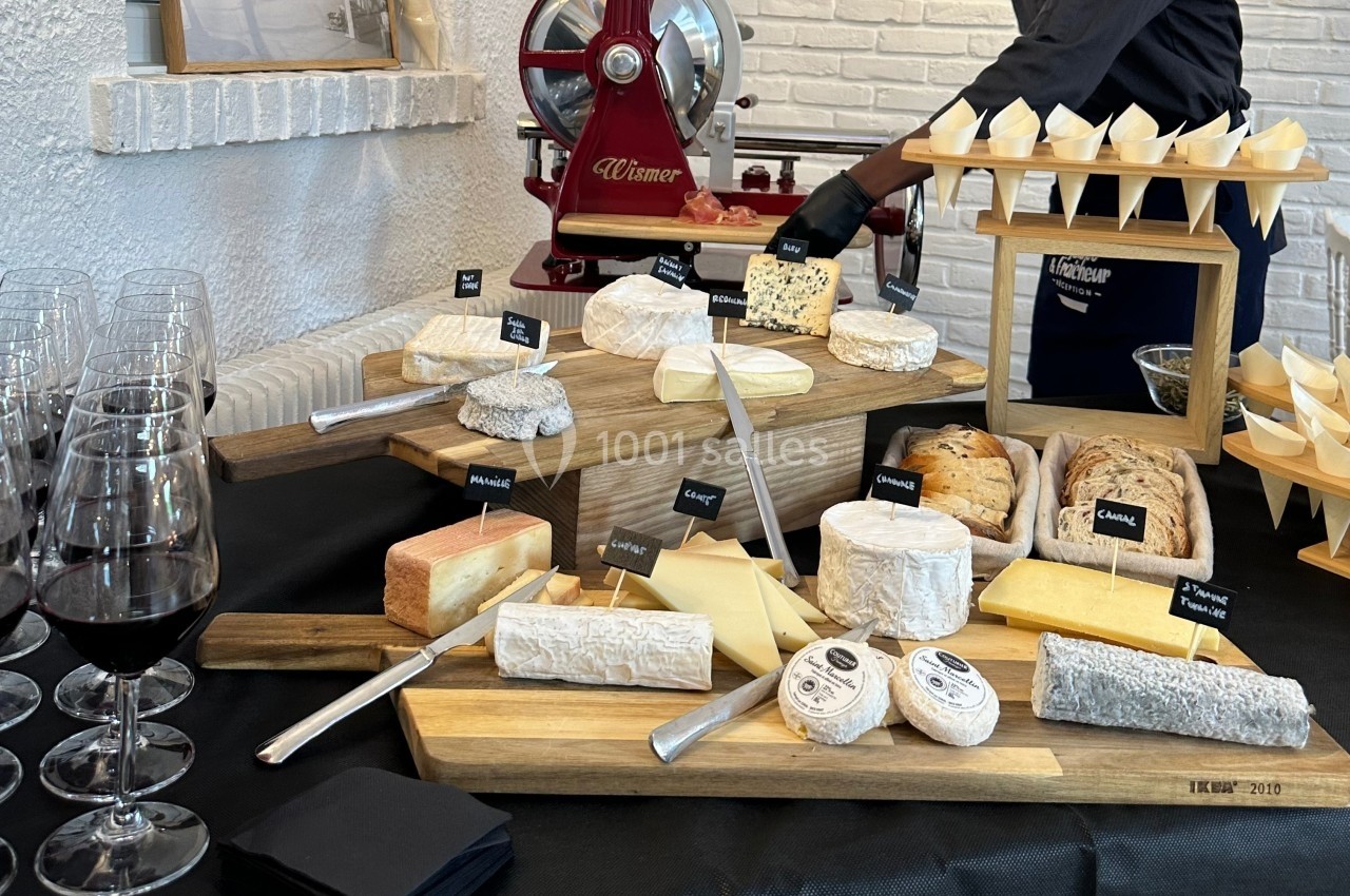 Plateau de fromages variés disposés sur des planches en bois, accompagné de couteaux et de verres de vin rouge.