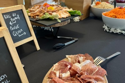 Plateau de mini-sandwiches variés, wraps et brochettes apéritives avec tomates cerises, présenté dans une boîte ouverte.