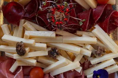Plateau de mini-sandwiches variés, wraps et brochettes apéritives avec tomates cerises, présenté dans une boîte ouverte.