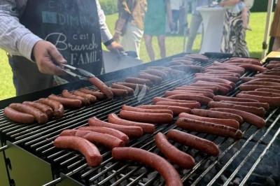 Miniature Traiteur Leers (Nord) - Tendance et Fraicheur Traiteur #17 Brochettes de viande et légumes grillant sur un barbecue en plein air, avec une fontaine et un jardin en arrière-plan.