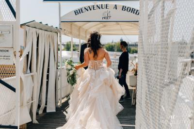 Un serveur en chemise blanche découpe du fromage sur une table garnie de mets, à bord d'un bateau.