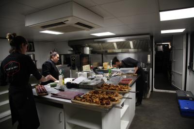 Trois cuisiniers préparent des plats dans une cuisine professionnelle équipée, avec des assiettes déjà dressées au premier…