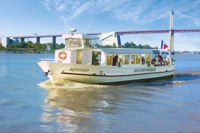 Bâtiment moderne en verre et métal près d'un fleuve, avec un bateau blanc amarré au premier plan.
