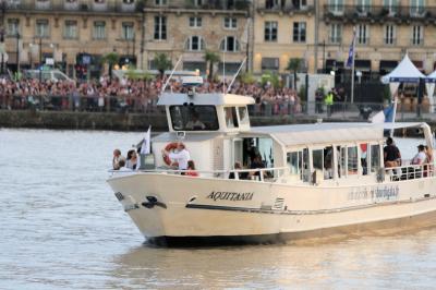 Bâtiment moderne en verre et métal près d'un fleuve, avec un bateau blanc amarré au premier plan.
