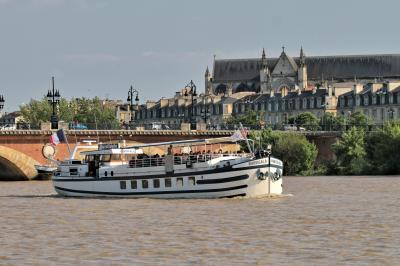 Bâtiment moderne en verre et métal près d'un fleuve, avec un bateau blanc amarré au premier plan.