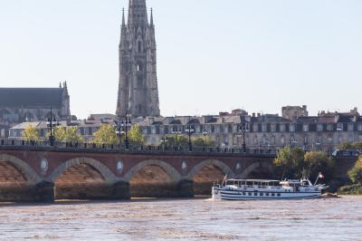 Bâtiment moderne en verre et métal près d'un fleuve, avec un bateau blanc amarré au premier plan.
