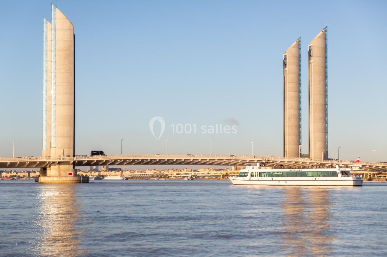 Un bateau navigue sur un fleuve sous un pont levant moderne avec des pylônes verticaux, par temps clair.