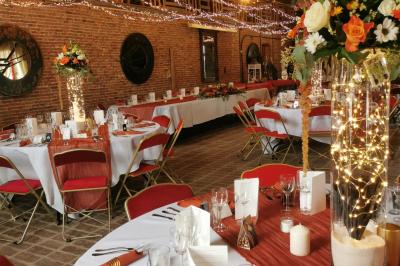 Un couple en tenue de mariage se tient devant un officiant dans un décor festif avec sapins et guirlandes lumineuses.