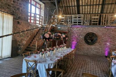 Un couple en tenue de mariage se tient devant un officiant dans un décor festif avec sapins et guirlandes lumineuses.