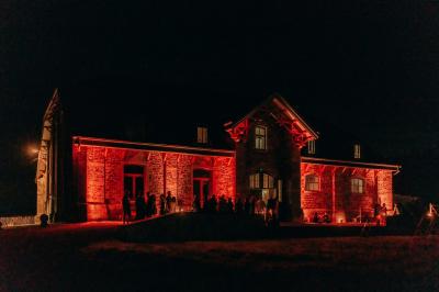 Un couple en tenue de mariage se tient devant un officiant dans un décor festif avec sapins et guirlandes lumineuses.