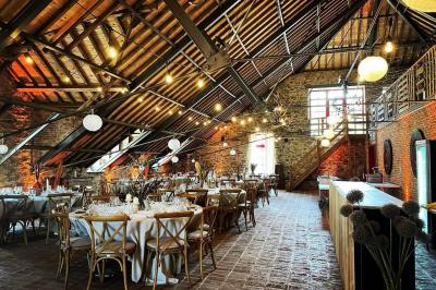 Un couple en tenue de mariage se tient devant un officiant dans un décor festif avec sapins et guirlandes lumineuses.