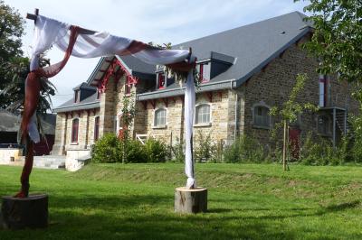 Un couple en tenue de mariage se tient devant un officiant dans un décor festif avec sapins et guirlandes lumineuses.
