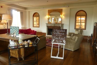 Un couple en tenue de mariage se tient devant un officiant dans un décor festif avec sapins et guirlandes lumineuses.