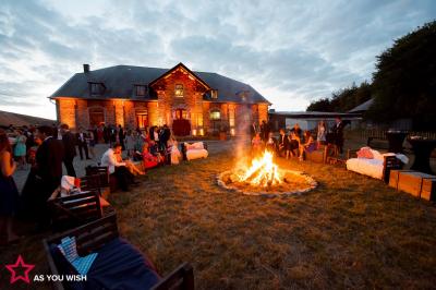 Un couple en tenue de mariage se tient devant un officiant dans un décor festif avec sapins et guirlandes lumineuses.