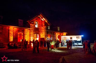 Un couple en tenue de mariage se tient devant un officiant dans un décor festif avec sapins et guirlandes lumineuses.