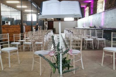 Un couple en tenue de mariage se tient devant un officiant dans un décor festif avec sapins et guirlandes lumineuses.