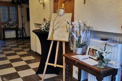 Un couple en tenue de mariage se tient devant un officiant dans un décor festif avec sapins et guirlandes lumineuses.
