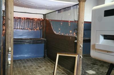 Un couple en tenue de mariage se tient devant un officiant dans un décor festif avec sapins et guirlandes lumineuses.