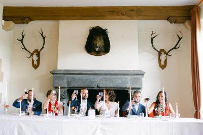 Un couple en tenue de mariage se tient devant un officiant dans un décor festif avec sapins et guirlandes lumineuses.