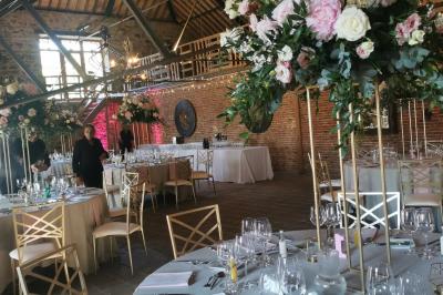Un couple en tenue de mariage se tient devant un officiant dans un décor festif avec sapins et guirlandes lumineuses.