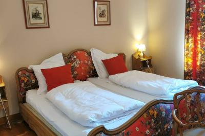 Porte d'entrée rouge à double battant ouverte, entourée d'un mur en pierre, avec des pots de fleurs de chaque côté.