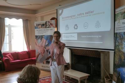 Porte d'entrée rouge à double battant ouverte, entourée d'un mur en pierre, avec des pots de fleurs de chaque côté.