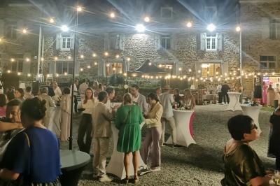 Porte d'entrée rouge à double battant ouverte, entourée d'un mur en pierre, avec des pots de fleurs de chaque côté.