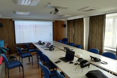 Porte d'entrée rouge à double battant ouverte, entourée d'un mur en pierre, avec des pots de fleurs de chaque côté.