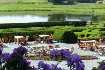 Porte d'entrée rouge à double battant ouverte, entourée d'un mur en pierre, avec des pots de fleurs de chaque côté.
