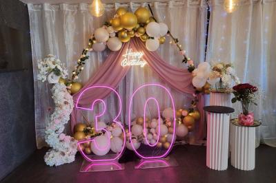 Figurines de mariés sur un gâteau décoré de fleurs bleues, d'une feuille argentée et d'un cœur en arrière-plan.
