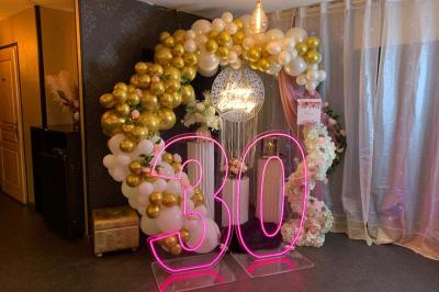 Figurines de mariés sur un gâteau décoré de fleurs bleues, d'une feuille argentée et d'un cœur en arrière-plan.