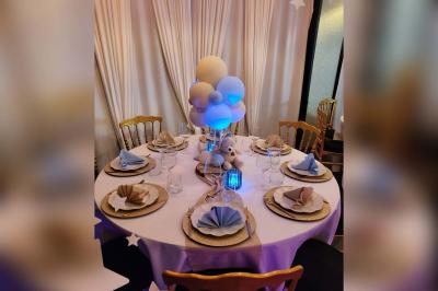 Figurines de mariés sur un gâteau décoré de fleurs bleues, d'une feuille argentée et d'un cœur en arrière-plan.