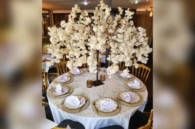 Figurines de mariés sur un gâteau décoré de fleurs bleues, d'une feuille argentée et d'un cœur en arrière-plan.